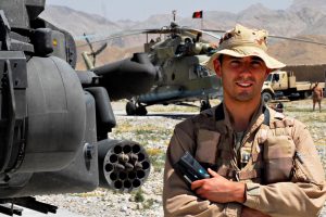 Roy de Ruiter naast een Apache-gevechtshelikopter in Afghanistan.